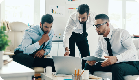Three colleagues reviewing work together on a laptop